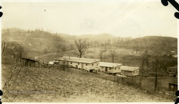 Barracks set up on a hill. There is a cemetery in the background.