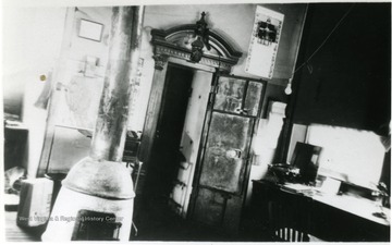 Interior of Fire Creek Office. Stove is in the center of the room and a desk and cabinet is off to the left.