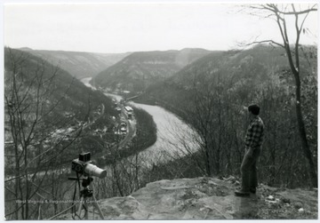 Man with camera is standing on flatrock with camera overlooking Thurmond and the river.