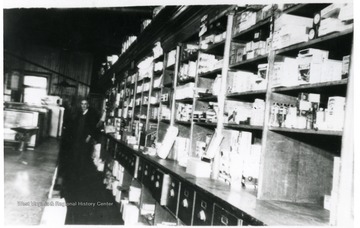 Shelves and drawers in the Fire Creek Store. There is a man in the back of the store.