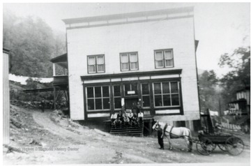 Men sit on steps of Dunedin company store, Shorty Bender horse and wagon also in front.