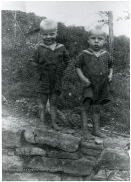 Two boys stand on a rock wall. 'Gloomy and Bonnie's.'