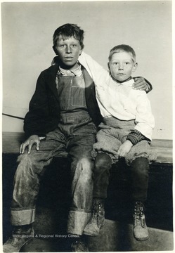 Two freckled faced boys sit on a bench.