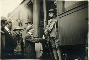 Trooper on train shakes hand of man on platform.