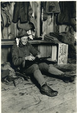 Man is sitting on the floor assembling his rifle.