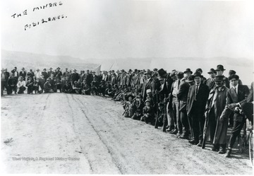 Miners crowd outside of tent.