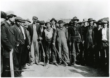 Miners crowd together with guns at side.