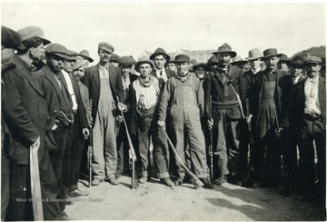 Miners crowd together with guns by their sides.