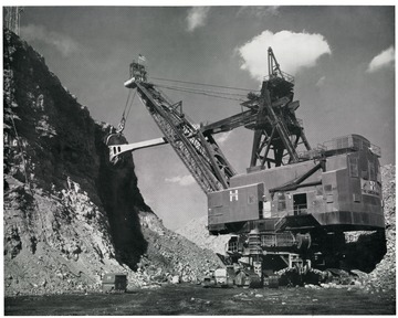 '50 Cubic-Yard Shovel at Georgetown No. 12 Mine of Hanna Coal Company, Division of Pittsburgh Consolidation Coal Company: These electric shovels are used to remove the earth and rock overburden from the coal seam. In a month's time, they will each remove as much as 1,600,000 cubic yards, or some 2,400,000 tons. If this material were to be loaded into open railroad cars, it would fill some 48,000 of them.'