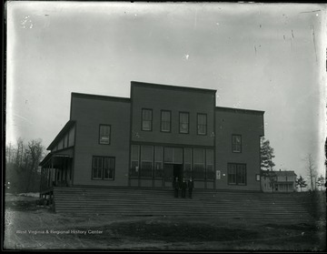 Three men stand on the steps of a Stuart Colliery Co. building. On the left side is a sign for Adams Express Company.