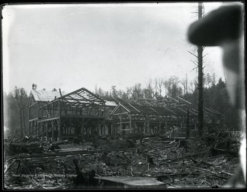 Men stand on the wooden frame of a large structure.