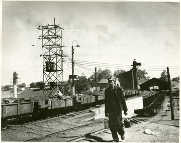 Men carrying cans along track with coal cars. 