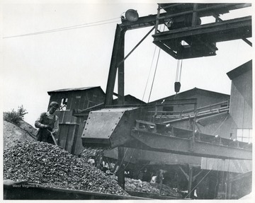 Miner shoveling coal as it pours into a coal car.