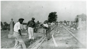 Three men build wooden forms for a driveway through the Miner's Cemetery in Mt. Olive, Illinois.