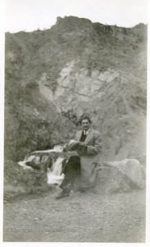 Joe Ozanic sitting on a rock on a hillside.