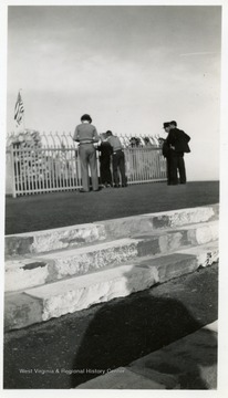 People view a fenced memorial or grave.