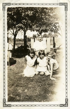 Man sitting in a chair with three girls sitting at the foot of the chair. 