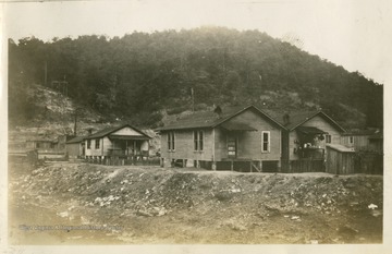 Group of small houses on stilts near a creek or stream.  Photograph from Joe Ozanic scrapbook.