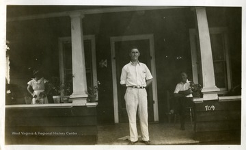 Men standing in the middle of the porch.  Others are standing on the side. 