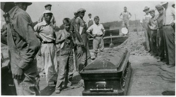 Workers stand around the uncovered casket of Mother Jones.