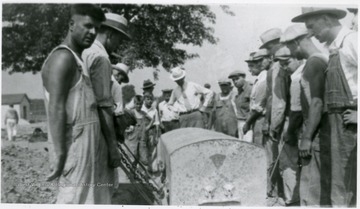 Men lift the vault from the grave site.