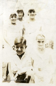 Three girls standing in the back.  A girl and a boy kneeling in the front.