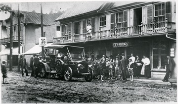 'Early auto in Alderson parked in front of Monroe St. entrance of Reynolds Co's Dept. Store with Trvoe Kittenger on porch.'
