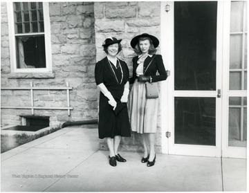 Two women pose for a portrait outside a building at Arthurdale, W. Va.