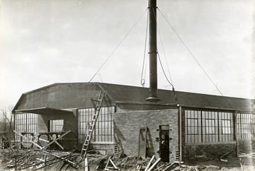 End of long, glass-walled building.  Smoke stack visible.