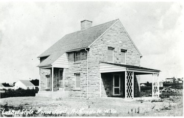 Two story stone house with side porch.