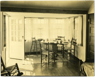 Interior view of homestead includes chairs and a table set up next to a window.