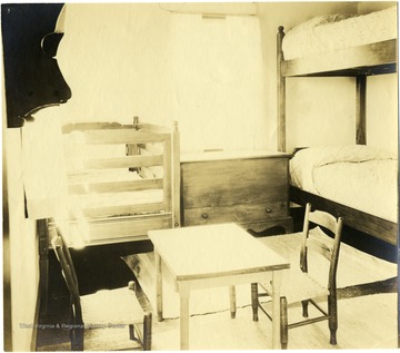 Interior view of nursery. Bunk beds, a crib, two small chairs and a table fill this nursery.