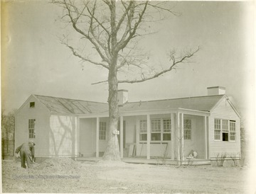 Man shoveling dirt outside house B-8. 