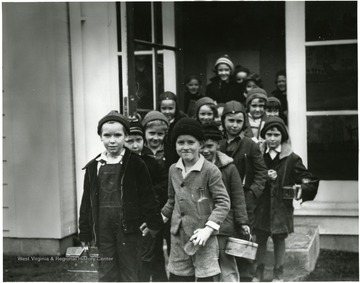 Smiling children walking out the door of the school.