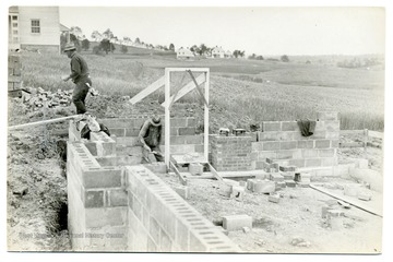 Men working at the corner of the foundation of a house in Arthurdale.