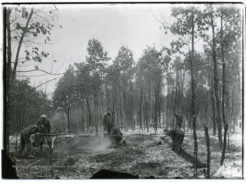 Men in the woods outline a foundation for the first house in Arthurdale.