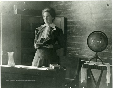 Flodie Cunningham holding a book at the front of the classroom.