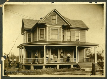 George Bair, Sr. and an unidentified man are standing in side yard. Mable Bair Saunders, Maggie Bair, and "Aunt Brook" (Mrs. George Bair, Sr.) are standing with three unidentified people on the front porch of a house in Beckley, West Virginia.