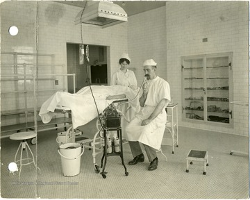 Doctor has a device at his mouth while nurse looks after the patient.