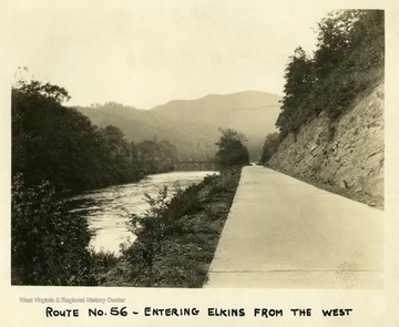 Route No. 56 which enters Elkins, West Virginia from the west. The road is next to a river.