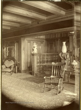 Wooden rocking chair in foreground of wood paneled sitting room in Halliehurst.
