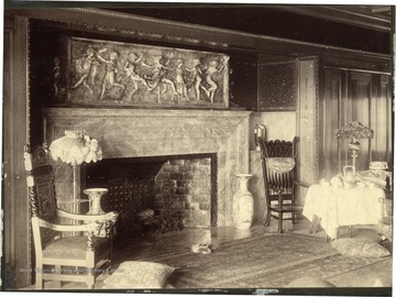 Fireplace has nice stone carving above it. Table set up with tea to the side of the fireplace.