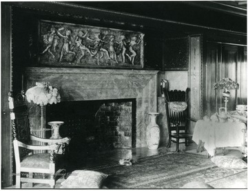 Fireplace has nice stone carving above it. Table set up with tea to the side of the fireplace.