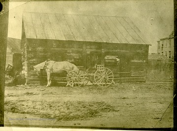A horse drawn wagon is in front of an unidentified log building in Fairmont, West Virginia.