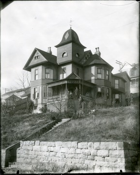 Large residence on a hill in Grafton, W. Va. People standing on a porch.
