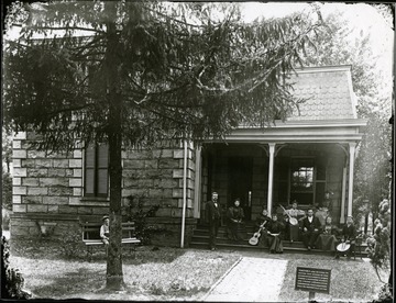 A group of musicians sits on the porch of the Superintendant's Lodge at the National Cemetery.