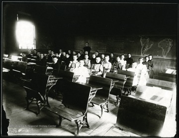 Students sitting in a classroom.  Teacher standing behind them at the chalkboard.  Grafton, W. Va.