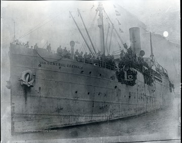 Men on board crowd to the sides of the ship.