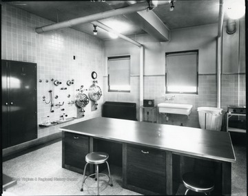 Hospital room with table and sink. Dials and a cupboard on the side wall.