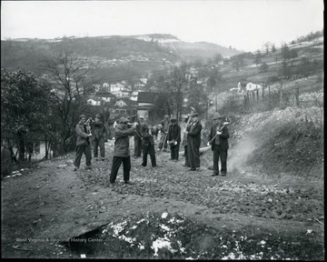 Group of men busting rocks with large hammers.